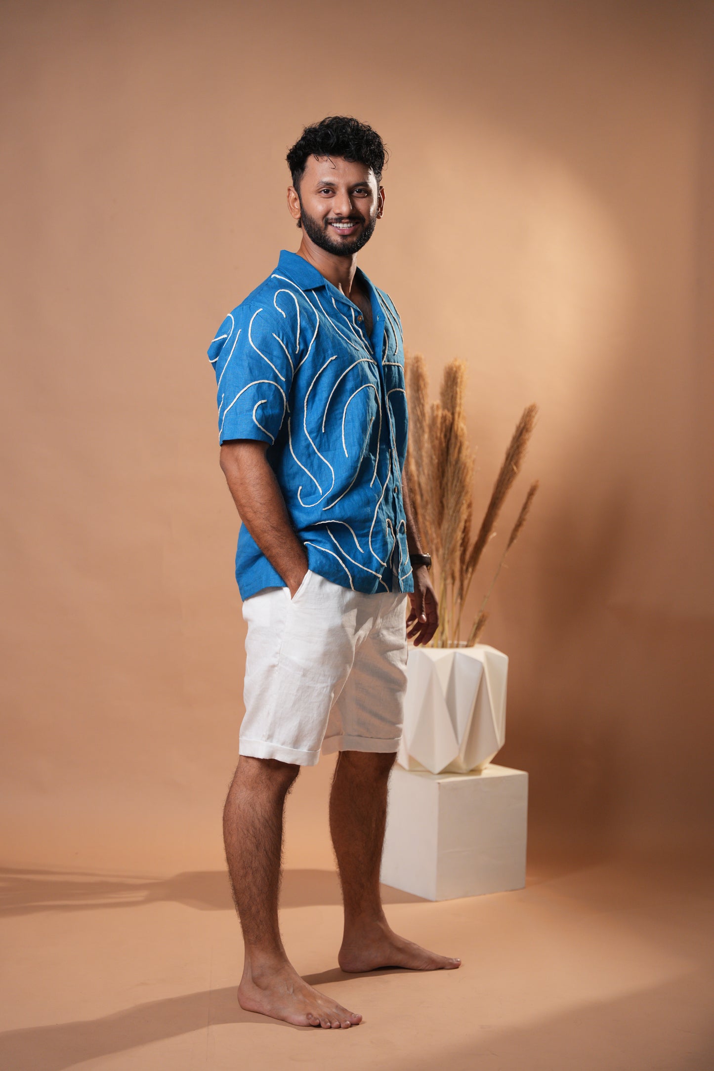 Men’s deep blue embroidered shirt, showcasing detailed patterns along the cuffs and collar.