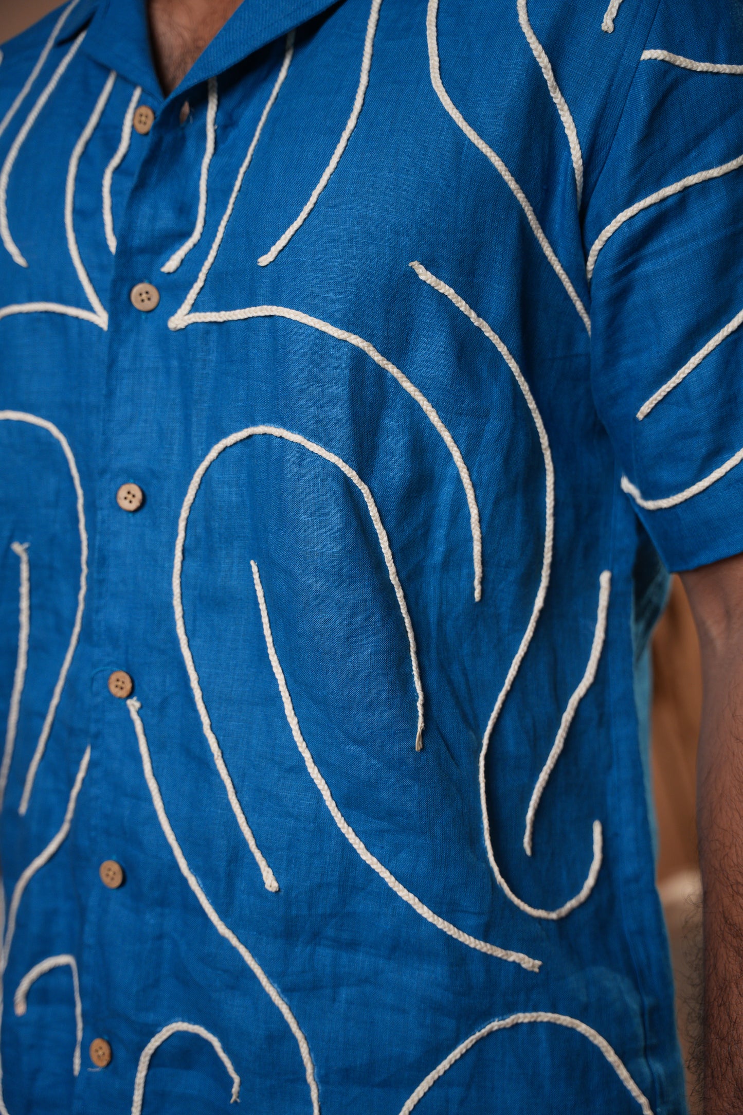 Close-up of a deep blue embroidered shirt, highlighting the fine threadwork and soft fabric.