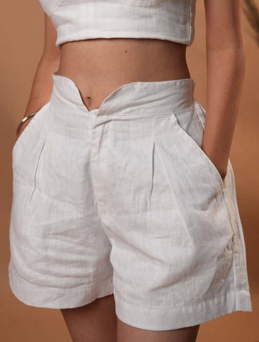 white shorts, showcasing the intricate pleating design and flowy fit.