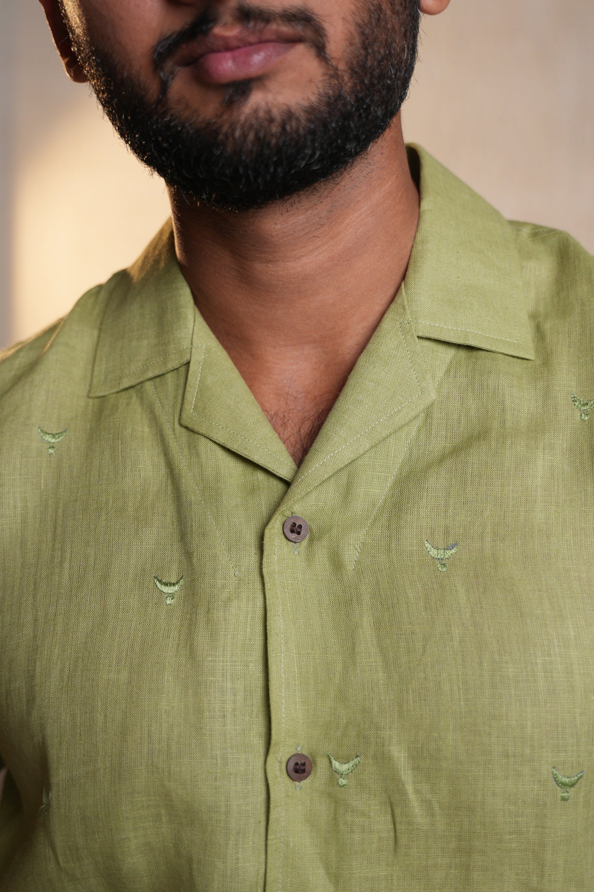 Close-up of a sage green embroidered shirt, highlighting the fine details and smooth texture.